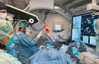Europa-Premiere: Diese Bildmontage zeigt, wie Oberarzt Dr. Kai Peter Friedrichs mit holografischer Medizintechnik am HDZ NRW arbeitet. Klinikdirektor Prof. Dr. Volker Rudolph (l. oben) und das Team im Herzkatheterlabor begleiten den Eingriff (Foto/Montage: HDZ NRW/DukkArt).