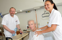 Politiker Axel Schäfer schenkt Patient Siegfried Sawatzki ein Glas Wasser ein, während Gesundheits- und Krankenpflegerin Jessica Gargulinski diesen stützt. Politiker Axel Schäfer schenkt Patient Siegfried Sawatzki ein Glas Wasser ein, während Gesundheits- und Krankenpflegerin Jessica Gargulinski diesen stützt.